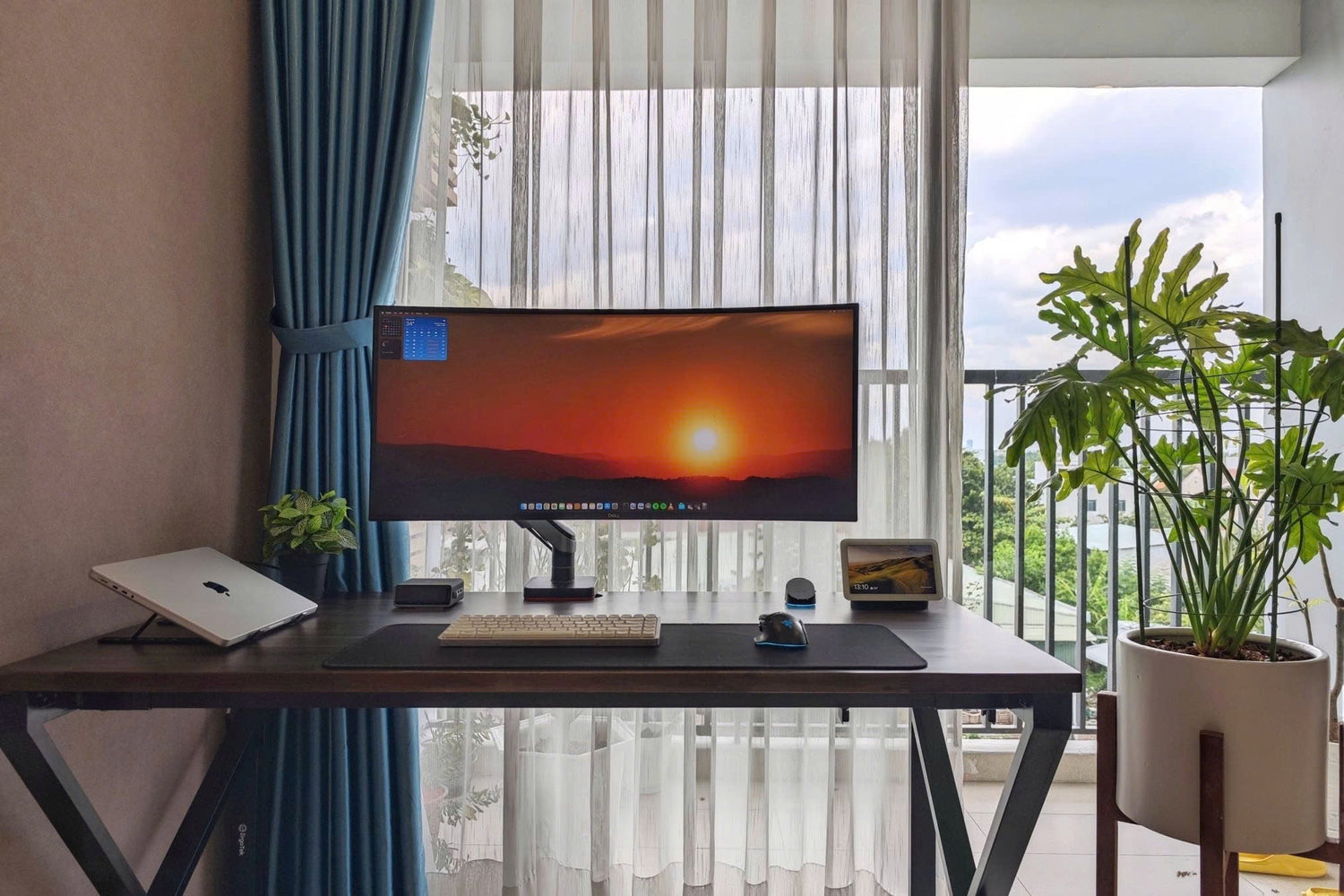 setup bàn làm việc tối giản với màn hình lớn và không gian gần cửa sổ nhiều ánh sáng tự nhiên